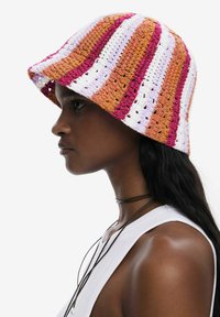 Häkel-Bucket-Hut mit rosa, orangefarbenen und weißen Streifen; breiter Rand; strukturierter Stoff; hat offene Maschen für Atmungsaktivität.