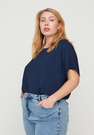 Navy blue short-sleeve top with a loose fit, paired with light-wash denim jeans featuring a high waist and two side pockets.