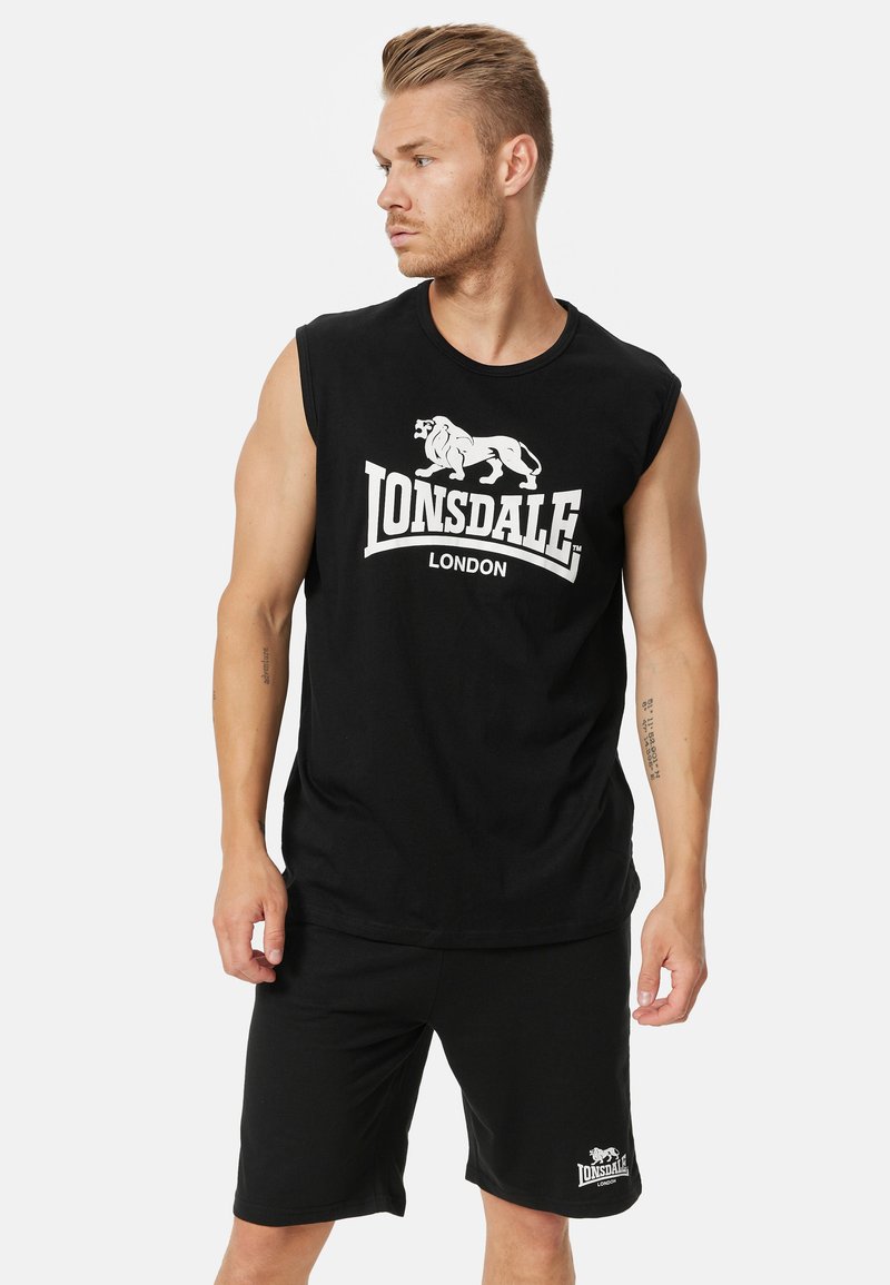 Juodas be Rankovių marškinėlis su baltu liūto grafiku ir užrašu "LONSDALE LONDON", derinamas su juodomis šortais su logotipu.