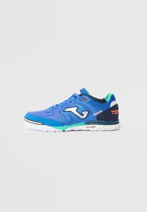 Blue athletic shoe with a textured fabric upper, white sole, contrasting black and green accents, and silver logo detail on the side.