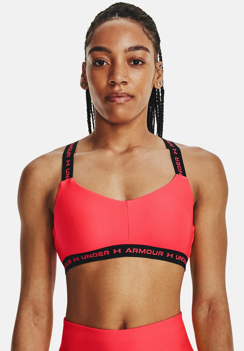 Soutien-gorge de sport rose avec une marque Under Armour noire sur les bretelles et la bande. Texture lisse, conçu pour les vêtements de sport, avec une coupe ajustée.