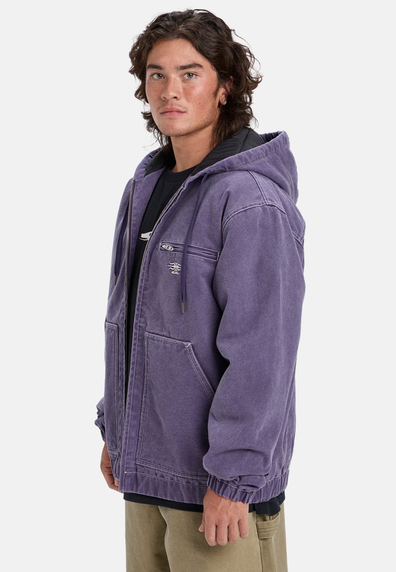 Purple denim jacket with a hood, front zipper, two side pockets, and elastic cuffs. Features an embroidered logo on the upper chest.
