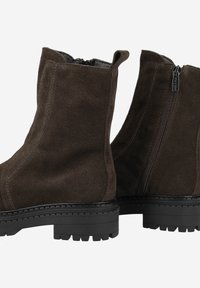 Bottes chevilles en suède marron avec une finition texturée, fermeture éclair sur le côté et semelle en caoutchouc noir présentant un motif de semelle robuste.