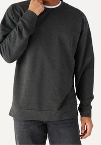Sudadera gris oscuro hecha de una tela suave, con un cuello redondo, mangas largas y un fit relajado con un dobladillo recto.