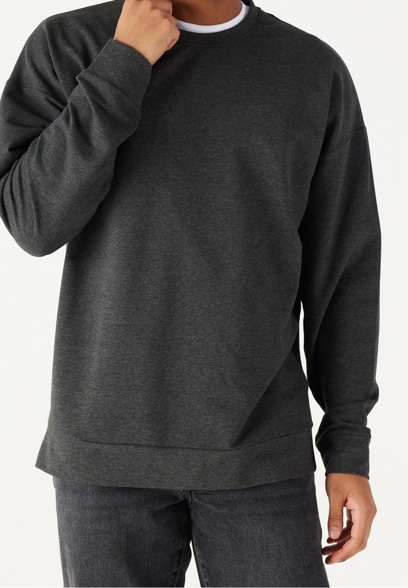 Sudadera gris oscuro hecha de una tela suave, con un cuello redondo, mangas largas y un fit relajado con un dobladillo recto.