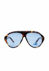 Occhiali da sole tartarugati con lenti blu, montatura geometrica e aste spesse. Etichetta di protezione UV visibile sulla lente sinistra.