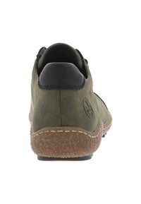 Scarpa in suede verde con tacco in pelle nera, suola testurizzata beige e cuciture visibili lungo il sottopiede. Dettaglio del logo sul lato.