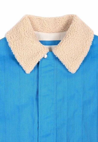 Veste bleue avec un col sherpa beige et duveteux et une fermeture à boutons dissimulée sur le devant.