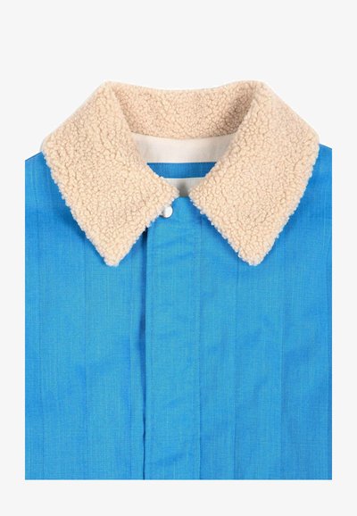 Veste bleue avec un col sherpa beige et duveteux et une fermeture à boutons dissimulée sur le devant.