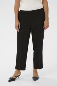Pantalon noir sur mesure avec une coupe droite, une ceinture élastique et une texture lisse, associé à des chaussures noires à bouts pointus ornées d'un nœud.