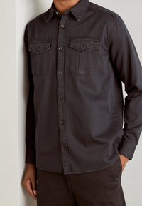 Dunkelgraues Langarmhemd aus Baumwolle mit Button-Down-Kragen, zwei Brusttaschen und durchgehender Knopfleiste.