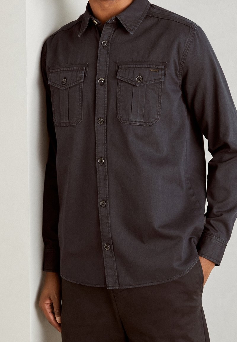 Dunkelgraues Langarmhemd aus Baumwolle mit Button-Down-Kragen, zwei Brusttaschen und durchgehender Knopfleiste.