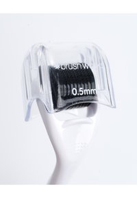 Vit dermaroller med ett klart plastskydd som visar svarta mikronålar (0,5 mm) och texturerat grepp för enkel användning.