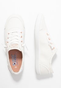 White canvas sneakers with a rounded toe, orange eyelets, and lace-up design. Features a textured sole and memory foam insole.