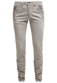 Pantalon gris clair ajusté avec une texture lisse, doté de chevilles froncées et d'ouvertures décoratives sur les poches avant.