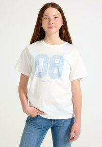 Hvid bomulds t-shirt med et stort lyseblåt mønstret "08" grafik og "Tres Chic" tekst. Klassisk pasform med korte ærmer og rund halsudskæring.