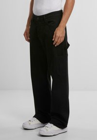 Pantaloni cargo negri cu un croi lejere, având un buzunar lateral și un design clasic cu cinci buzunare. Fabricat dintr-un material de bumbac robust.