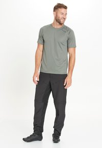 Vihreä kevyestä meshistä valmistettu t-paita, jossa on lyhyet hihat ja hillitty kuvio, yhdistettynä mustiin housuihin, joissa on kapenevat lahkeet ja vahvistetut yksityiskohdat.