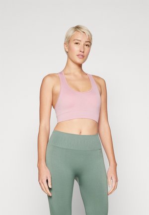 Rosa sports bh i kort modell laget av glatt stoff, kombinert med ribbede, høyt liv grønne leggings. Enkelt design uten mønstre eller metallbeslag.