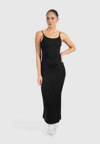 Schwarzes, figurbetontes Maxikleid mit dünnen Trägern, aus glattem Stoff, mit minimalistischer Gestaltung und knielangem Saum.