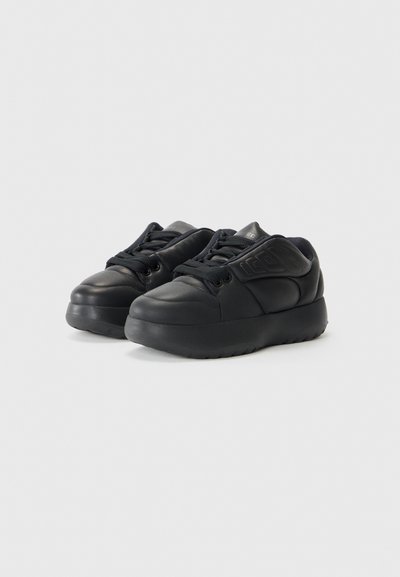 Zwarte sneakers van leer, met een ronde neus, textuurpaneel aan de zijkant en dikke rubberen zool. De veters zijn zwart, met een gevoerde kraag.