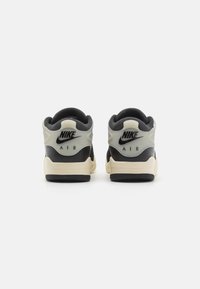 Nike sneakers med en sort overdel, grå detaljer og en cremefarvet sål. Har en polstret krave og hælflap med Nike-logoet.