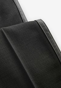 Tejido negro texturizado con un borde liso, que muestra un diseño plegado. El material parece duradero con un brillo sutil.