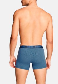 Blaue Boxershorts mit weicher Textur, ausgestattet mit einem dunkelblauen elastischen Bund mit "PUMA"-Markenlogo. Ansicht zeigt die Rückseite und Seiten.