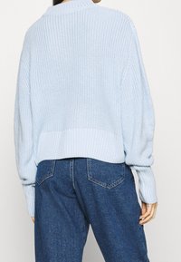 Vaaleansininen lyhyt neulepaita, jossa on ribbauskorsetti ja teksturoitu neule. Yhdistetty korkeavyötäröisiin tummaan farkkuleggingseihin. Pehmeä, kevyt kangas.