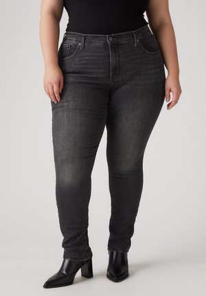 Black skinny jeans made of denim with subtle fading and distressed accents. High waist with front pockets. Paired with black heeled boots.