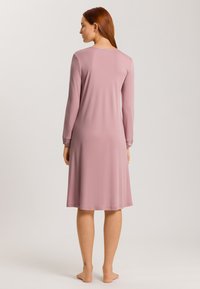 Yöhaalarit, joissa on pitkät hihat pehmeässä vaaleanpunaisessa kankaassa, kellottava leikkaus, polvipituinen, pyöreä pääntie, sileä rakenne, helmakin, joka lainehtii kevyesti.