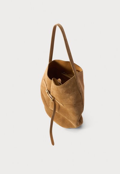 Bruine suède tote bag met een zachte textuur, enkele handgreep en ritssluiting. Lichtjes slonzige vorm met interne vakken zichtbaar.