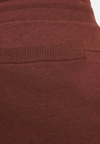 Maroon fabric with a smooth texture and ribbed waistband. Subtle horizontal lines in the knit pattern create visual interest.