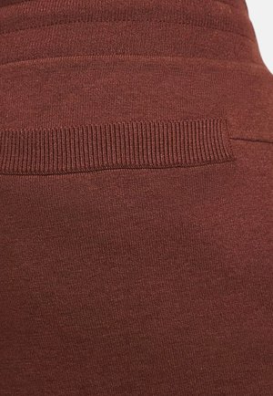 Tessuto bordeaux con una texture liscia e una vita a coste. Sottili linee orizzontali nel motivo a maglia creano interesse visivo.