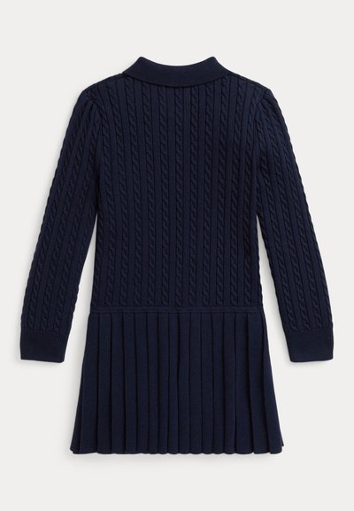 Mornarsko modra pletena obleka z rebrasto teksturo, ki ima ovratnik, dolge rokave in nabran krilo. Podrobnosti vključujejo vidno pleteno kabelsko vzorčenje.