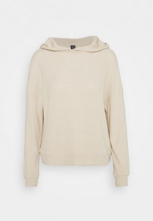 Beige gerippter Kapuzenpullover aus Strick mit langen Ärmeln, fallenden Schultern und enganliegenden Bündchen, vor weißem Hintergrund dargestellt.