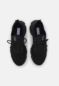 Černé sportovní boty s síťovaným svrchním materiálem, kulatou špičkou a texturovaným designem. Jsou vybaveny plochými tkaničkami a polstrovanou podrážkou pro pohodlí.