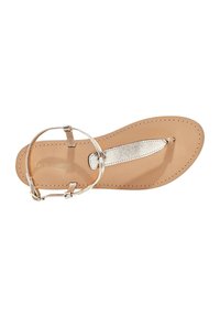Tan leather flat sandal with a metallic silver thong strap and ankle loop. Features stitched detailing and a smooth footbed.