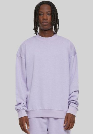 Sweatshirt oversized en lavande avec des manches longues, col et poignets côtelés, en matière polaire douce, surface légèrement texturée, coupe décontractée.