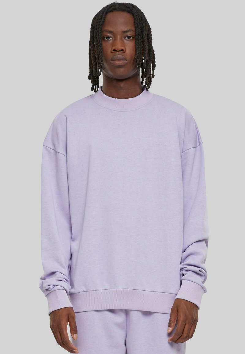 Sweatshirt oversized en lavande avec des manches longues, col et poignets côtelés, en matière polaire douce, surface légèrement texturée, coupe décontractée.