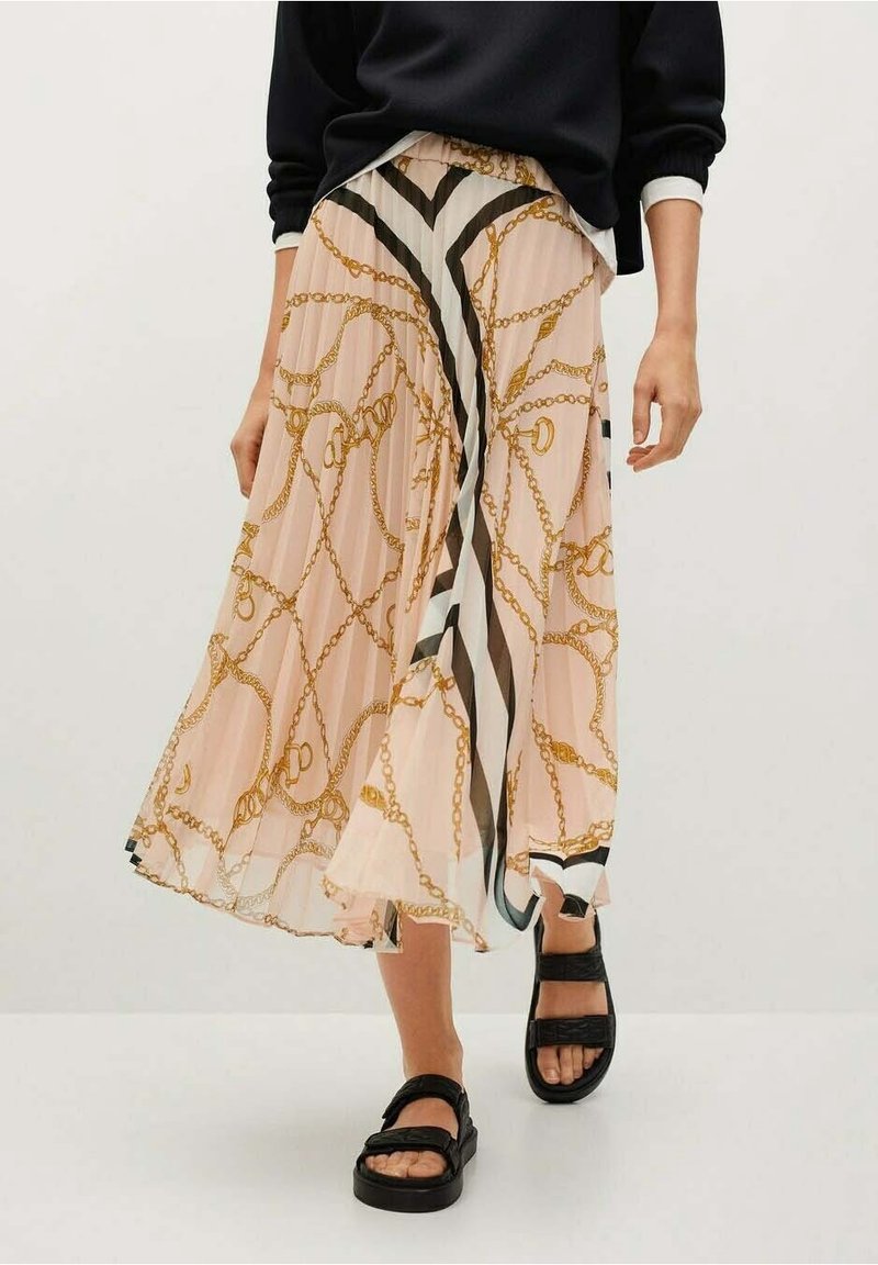 Gonna midi plissettata in chiffon rosa chiaro con motivo a catena dorata e strisce nere; abbinata a sandali neri chunky.