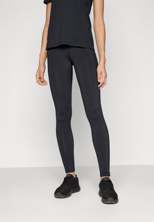 Sorte treningsleggings laget av elastisk stoff, med en glatt overflate og tett passform, kombinert med sorte treningssko.