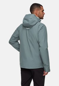 Lättviktsjacka med huva i dämpad teal, med en slät yta, elastiska ärmslut och en tight passform. Logotypen syns på den övre delen av ryggen.