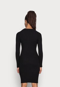 Robe noire en tricot avec manches longues, silhouette ajustée, texture côtelée et encolure ronde. Tissu lisse, design à longueur genou.