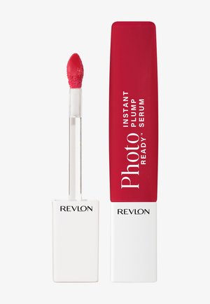 Sérum repulpant pour les lèvres rouges avec applicateur à baguette à côté d'un contenant fermé étiqueté "Photo Ready Instant Plump Serum" de Revlon sur fond blanc.