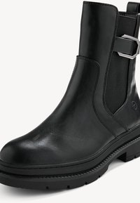 Bottine noire en cuir avec une semelle épaisse en caoutchouc, un panneau latéral élastique et un détail de boucle argentée sur le côté.