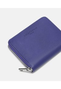 Kompaktowy niebieski skórzany portfel na zamek błyskawiczny z srebrnym zamkiem i wytłoczonym nazwiskiem marki na froncie.