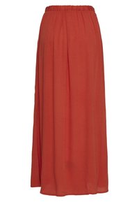 Jupe longue rouge en tissu léger, dotée d'une taille élastiquée et d'une coupe fluide qui crée un mouvement doux.