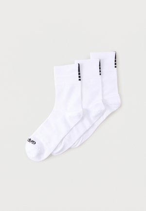 Τρία ζευγάρια λευκές κάλτσες στρατιωτικού τύπου με μαύρες ρίγες κοντά στην κορυφή και μαύρο κείμενο στα δάχτυλα, τοποθετημένα επικαλυπτόμενα σε ανοιχτό φόντο.