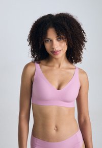 Roze draadloze beha met een gladde afwerking, brede banden en een diepe V-halsontwerp. Lichtgewicht materiaal dat een naadloze uitstraling biedt.